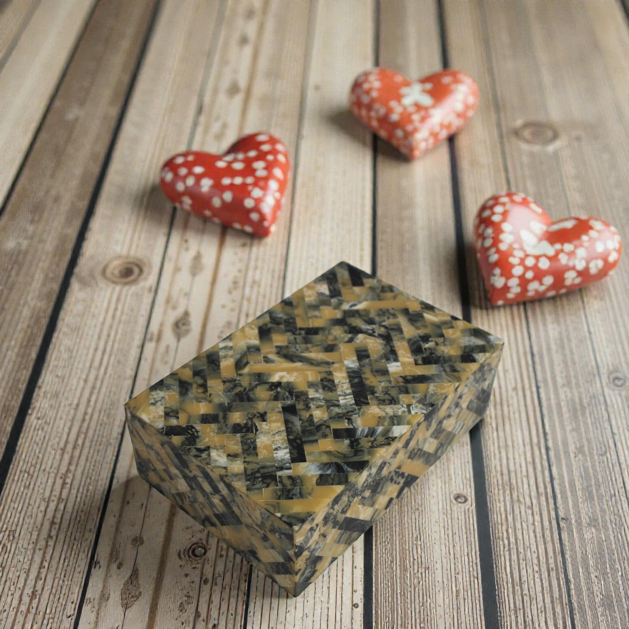  Decorative box with a woven pattern on a wooden surface with heart-shaped objects. 