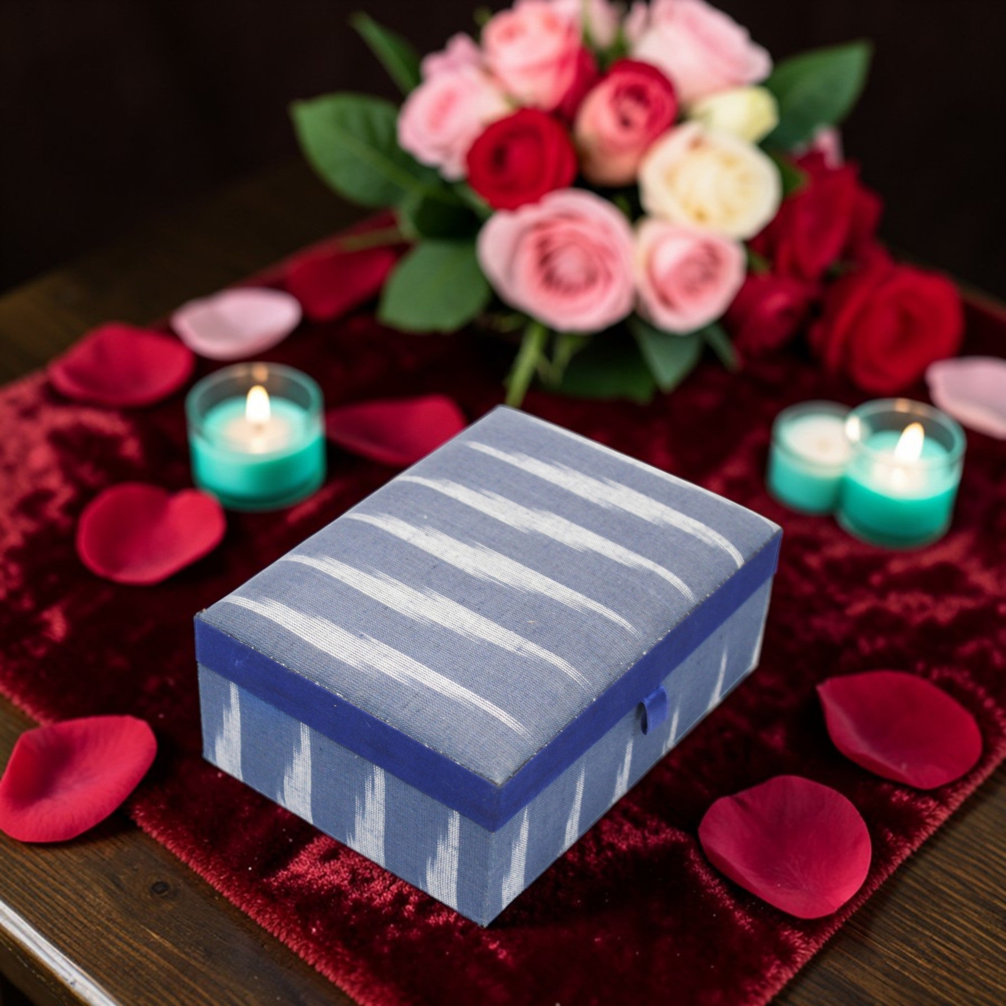  Blue striped box on a red surface with candles and flowers 