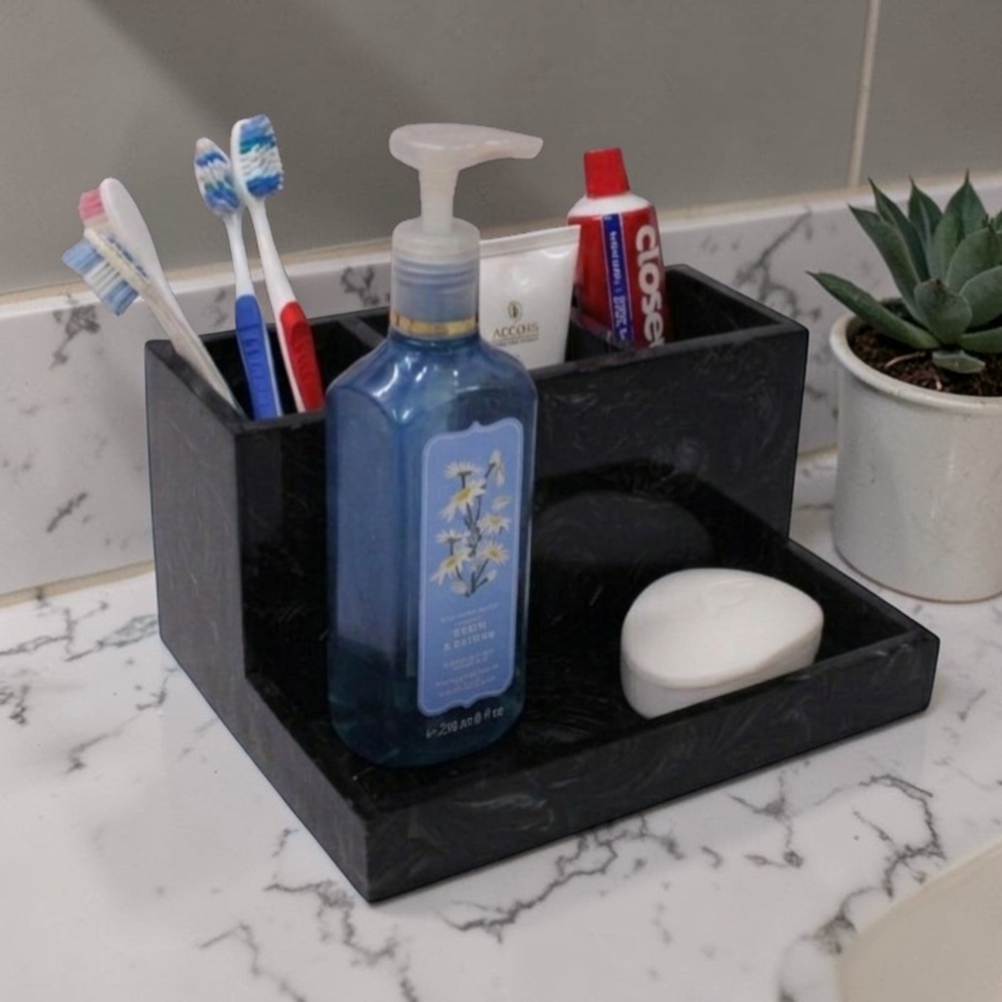  Black marble toothbrush holder with toiletries on a bathroom counter 
